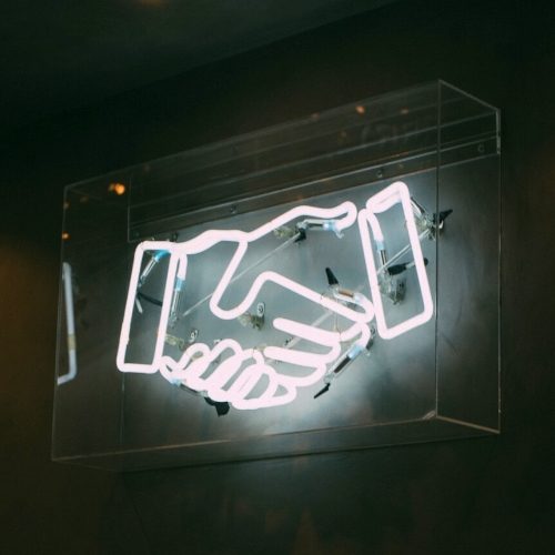 Neon sign with two hands shaking
